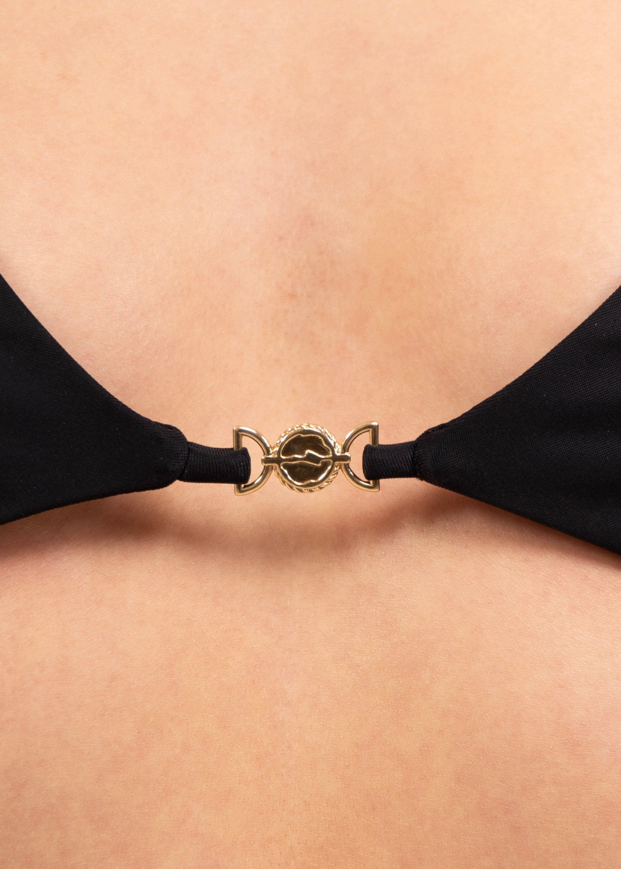 Close-up of the 18K gold-plated charm at the center of the May Rose Chia Ebène black bralette bikini top