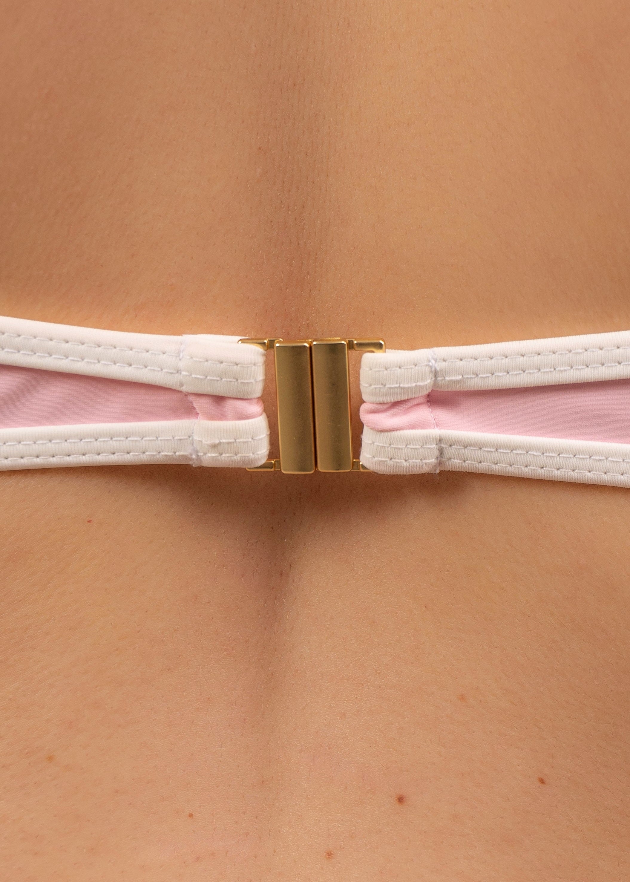 Close-up of the 18K gold-plated clip fastening on the May Rose Noah Ispahan pastel pink bikini top with white contrast strap