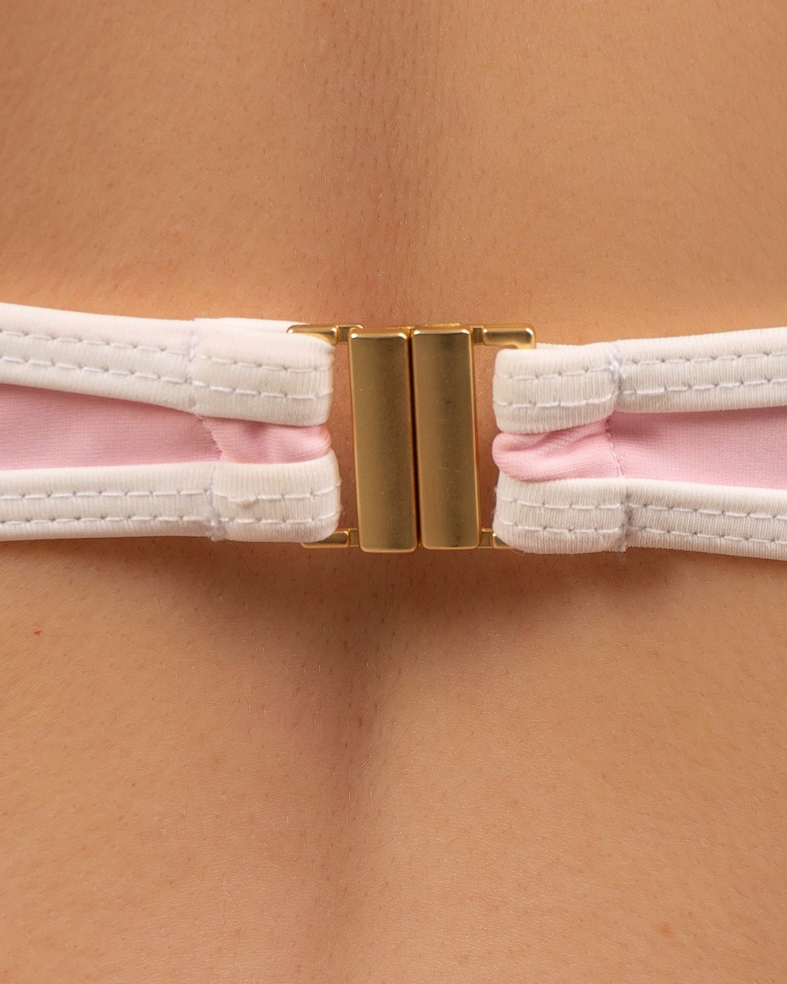 Close-up of the 18K gold-plated clip fastening on the May Rose Noah Ispahan pastel pink bikini top with white contrast strap