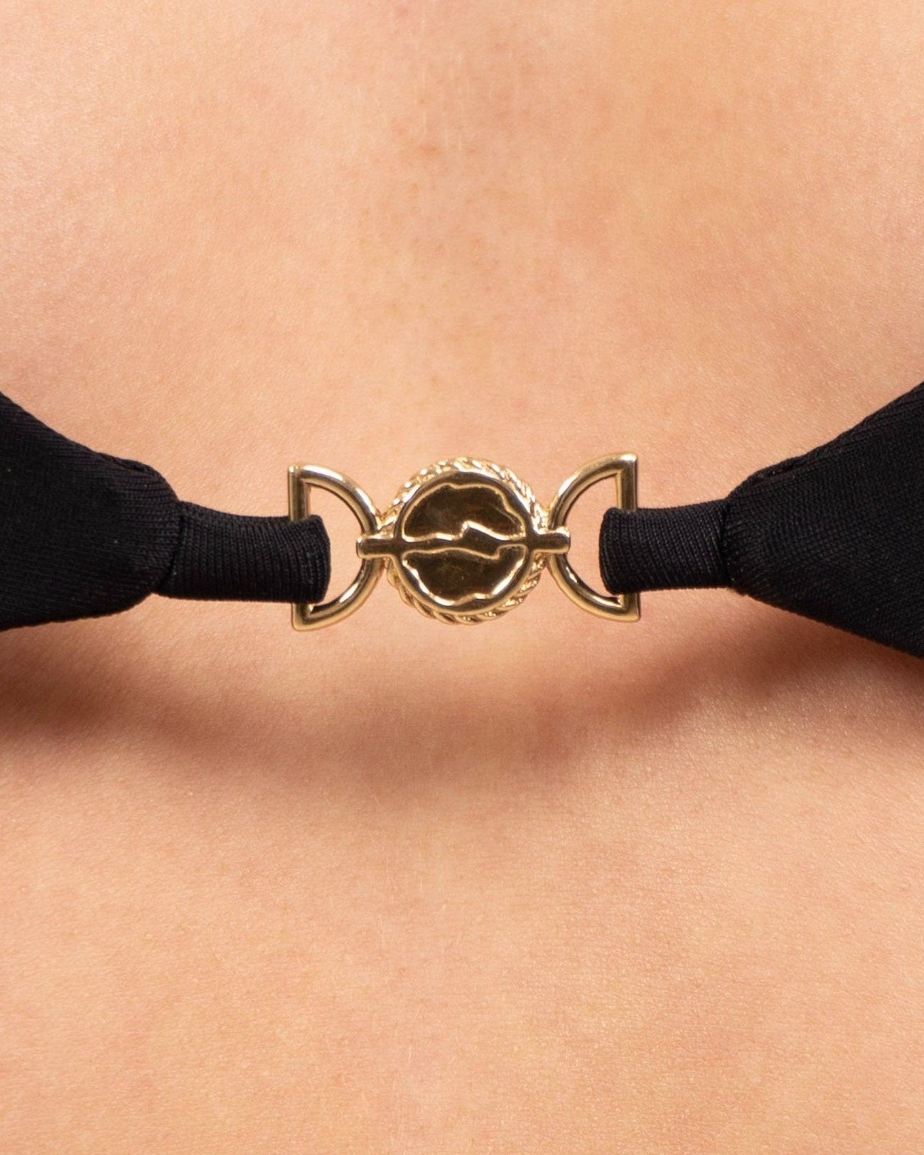 Close-up of the 18K gold-plated charm at the center of the May Rose Chia Ebène black bralette bikini top